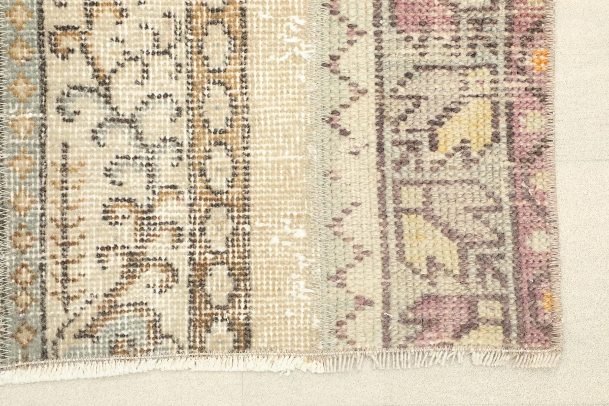 Close-up detail of the rug's fringe and the distinct patterns in beige, rose, and green.