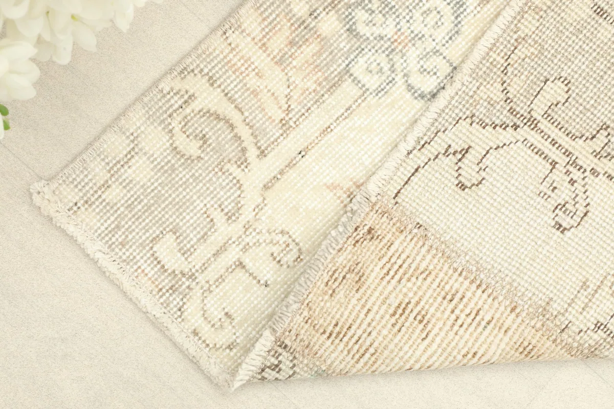 Corner of the rug folded back, revealing the reverse side of the hand-knotted wool pile on cotton foundation.