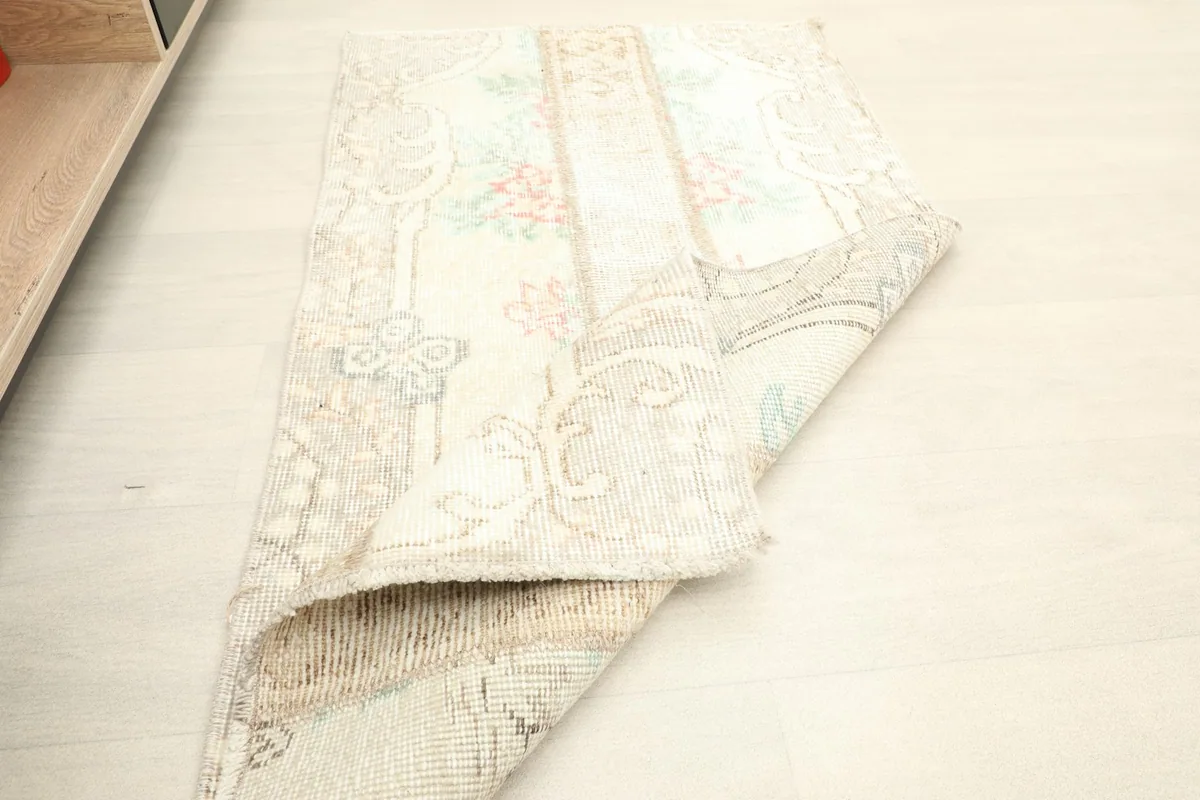 Rug partially folded, showing the flexibility and the intricate weaving on the back.