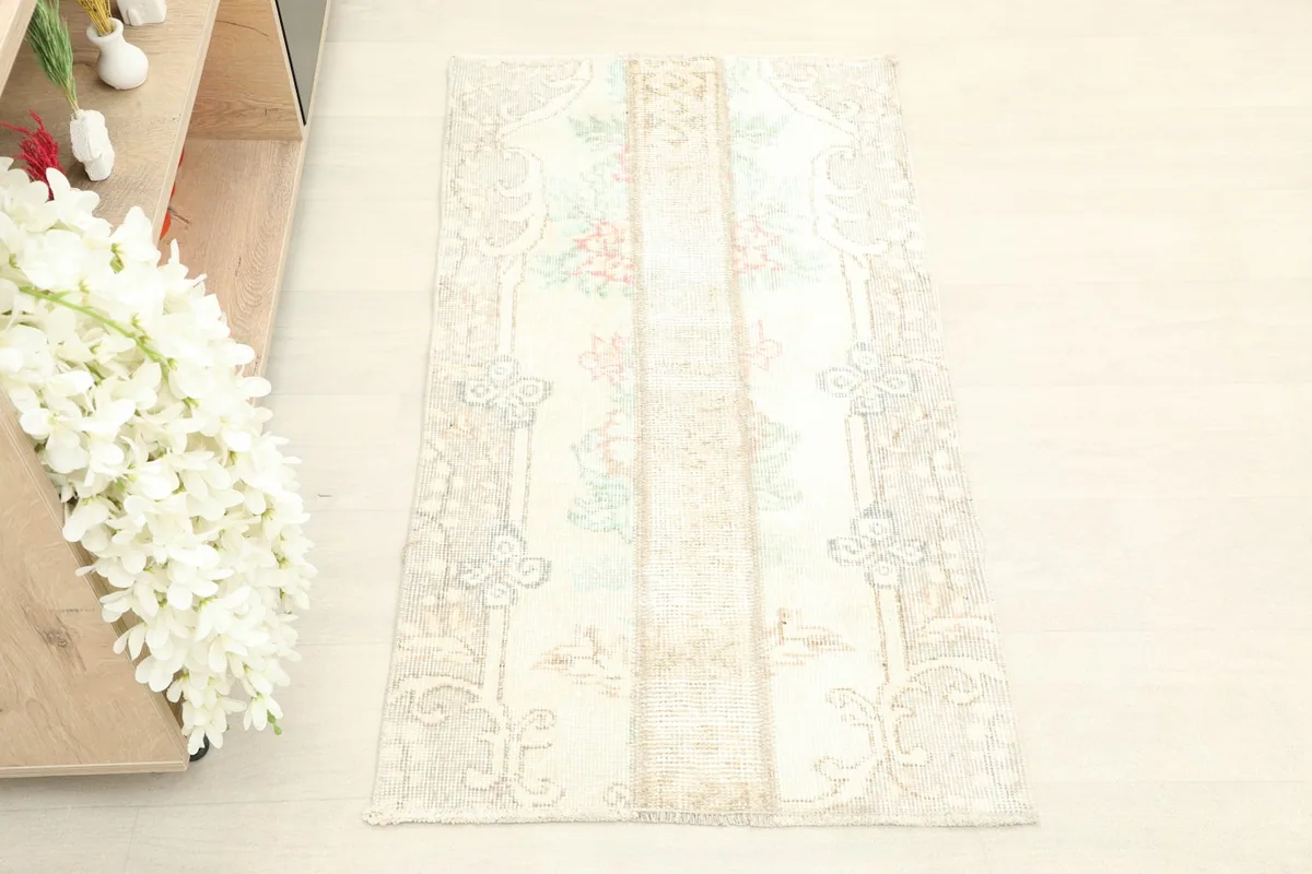 Overhead view of the vintage ivory rug, highlighting the floral and geometric panel design.