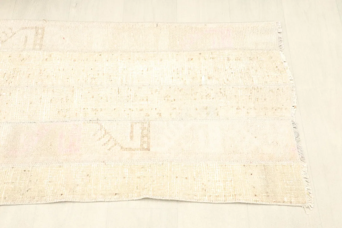 Side angle view of the beige rug, showing its rectangular shape and the short fringes