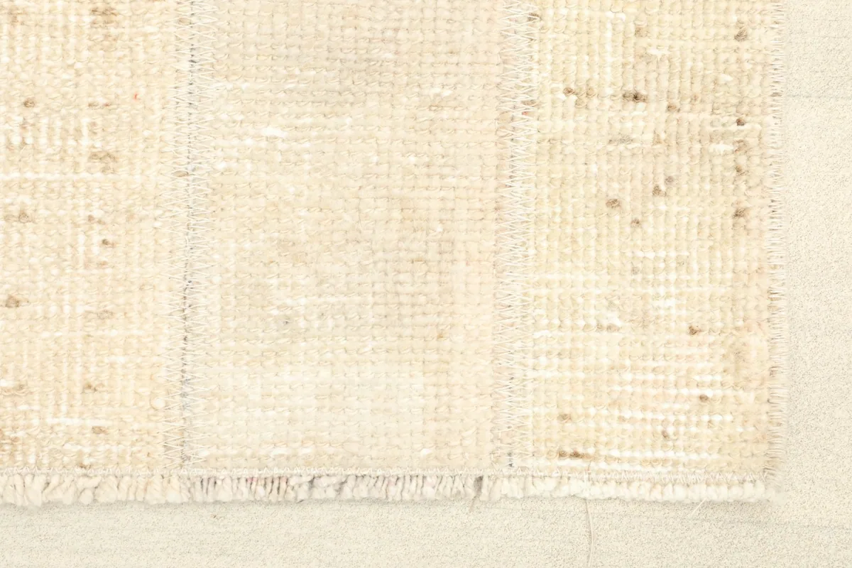 Close-up of the rug's texture and patchwork seams, showing the low wool pile and fringe