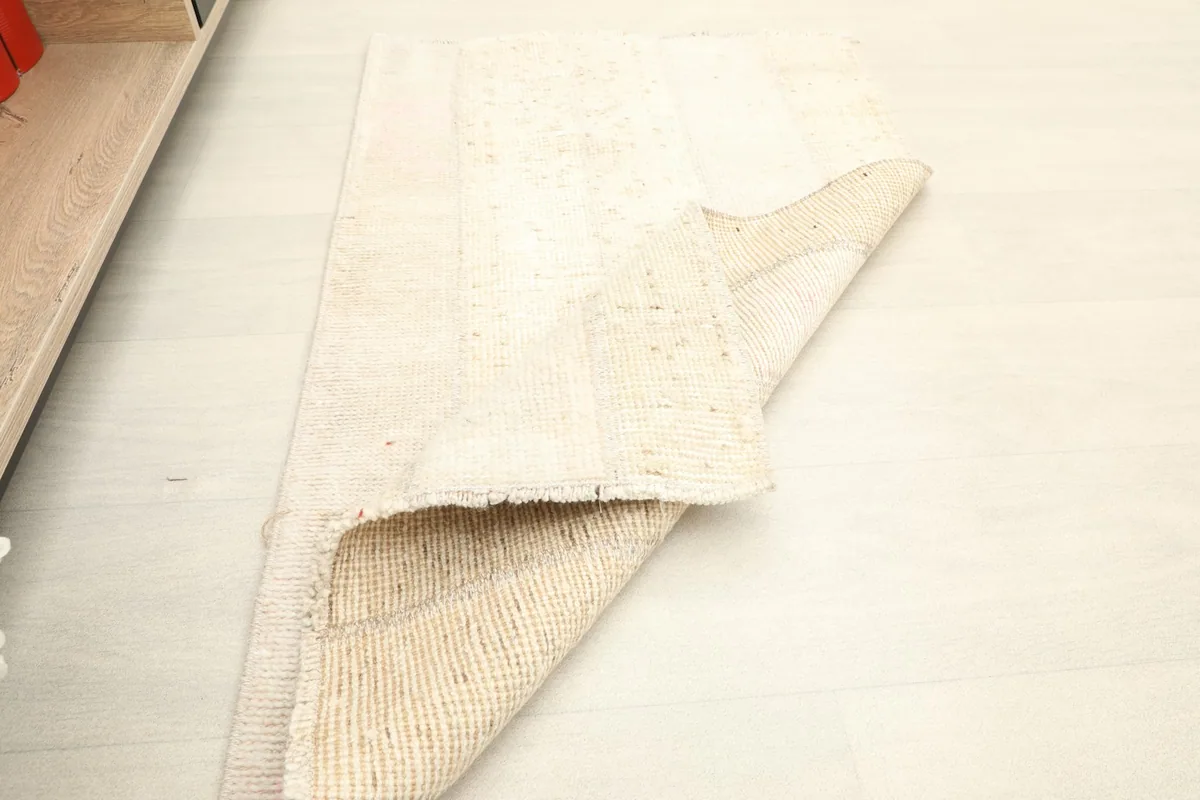 The vintage rug partially folded, displaying its flexibility and construction