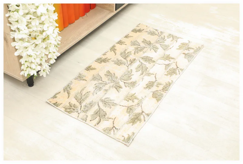 Full top view of the beige and olive floral vintage rug on a white background.
