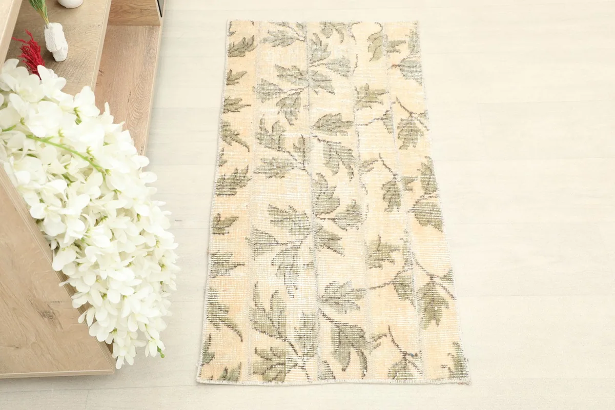 Overhead shot of the full vintage rug, highlighting its beige field and olive leaf pattern.