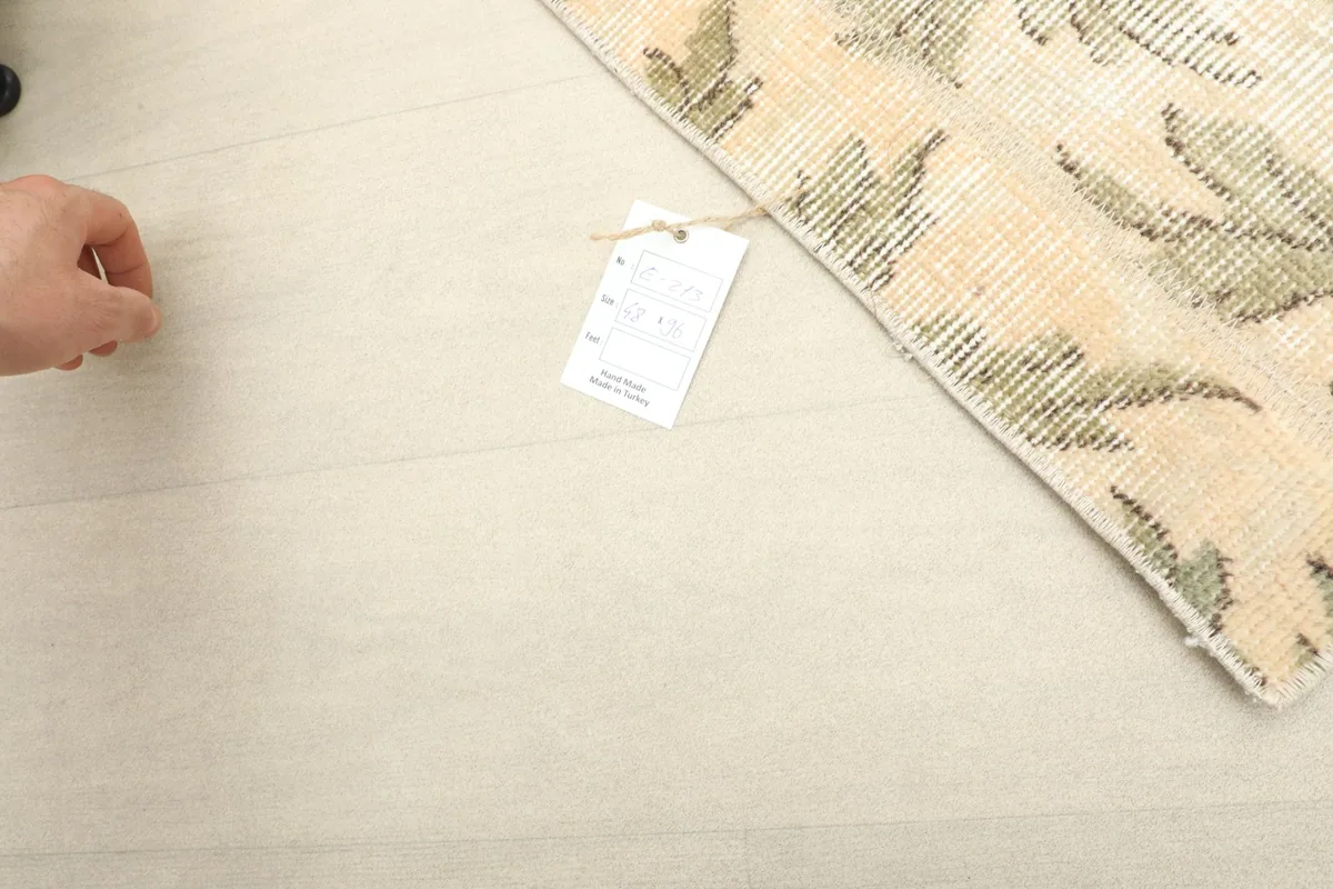 A hand next to the rug's tag, indicating the rug's size and origin.