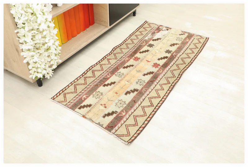 Full top view of the beige and rust vintage Anatolian rug on a white floor