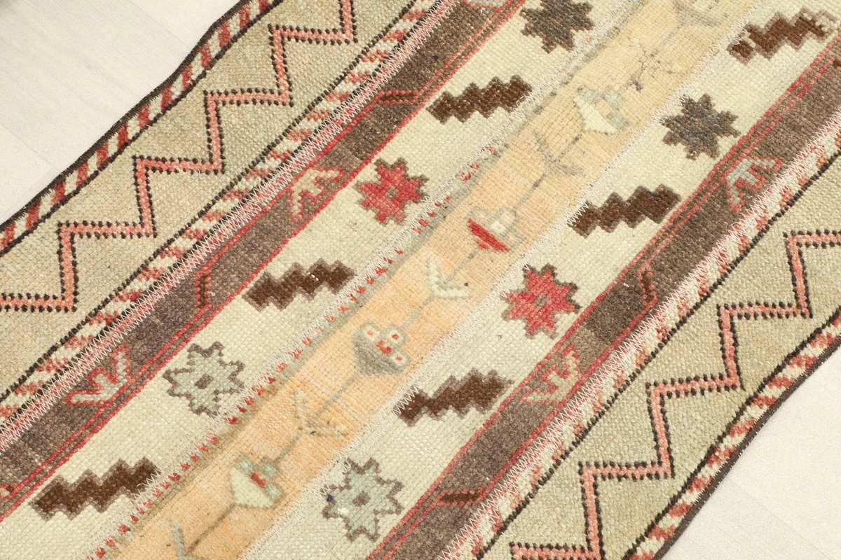 Angled view of the rug, highlighting the varied stripes of tribal motifs in beige, rust, and brown