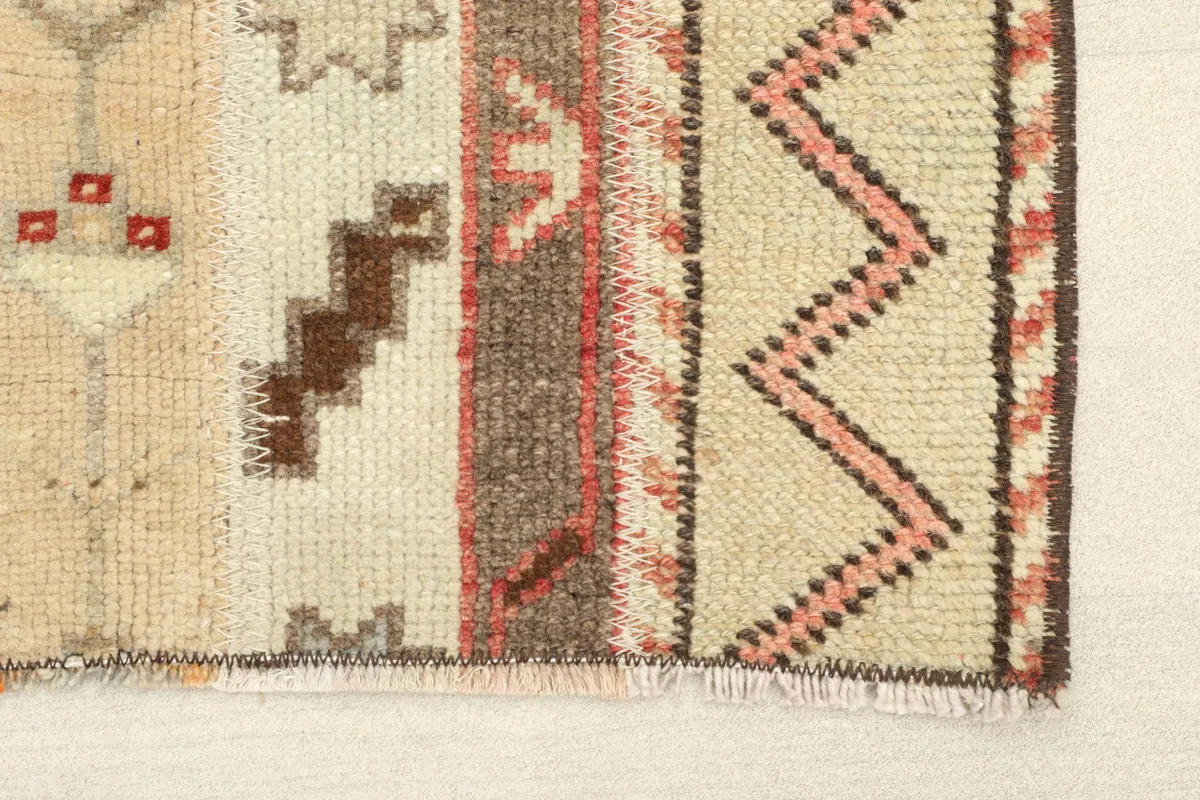 Close-up detail of the rug's edge, showing the beige field and rust zigzag border