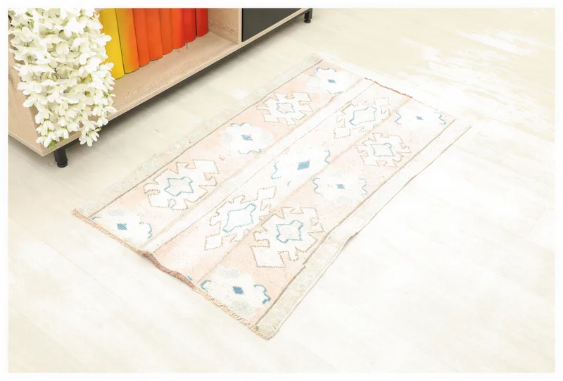 Full top view of the rose and blue geometric vintage Anatolian rug on a white background.