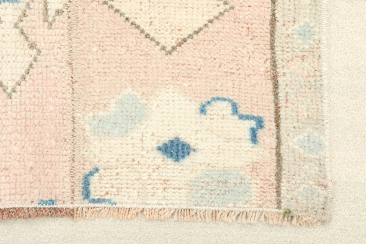 Close-up detail of the fringe and edge of the vintage rug, showing the knotting and color variation.