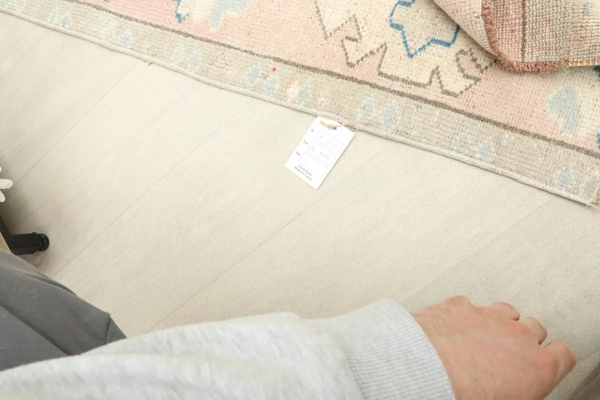 Close-up showing the rug's label and a hand for scale, emphasizing its mini size.