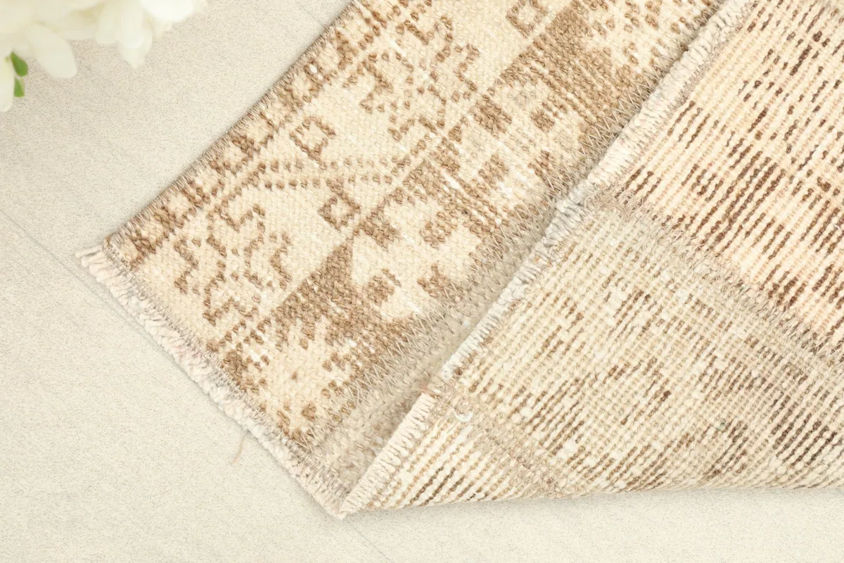 Corner of the rug folded to show the reverse side, revealing the hand-knotted cotton foundation.