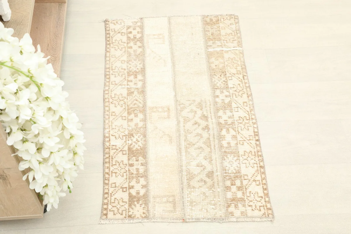 Overhead shot of the beige and tan vintage rug, highlighting its patchwork construction and patterns.