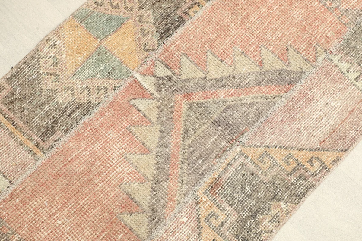 Angled view of the rust, charcoal, and beige rug, highlighting geometric patterns and color variations.