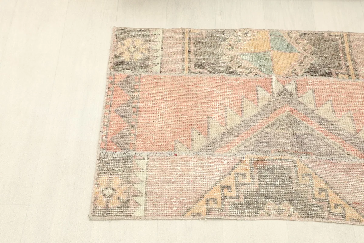 Angled view from the corner of the small rust patchwork rug, showing its overall shape.