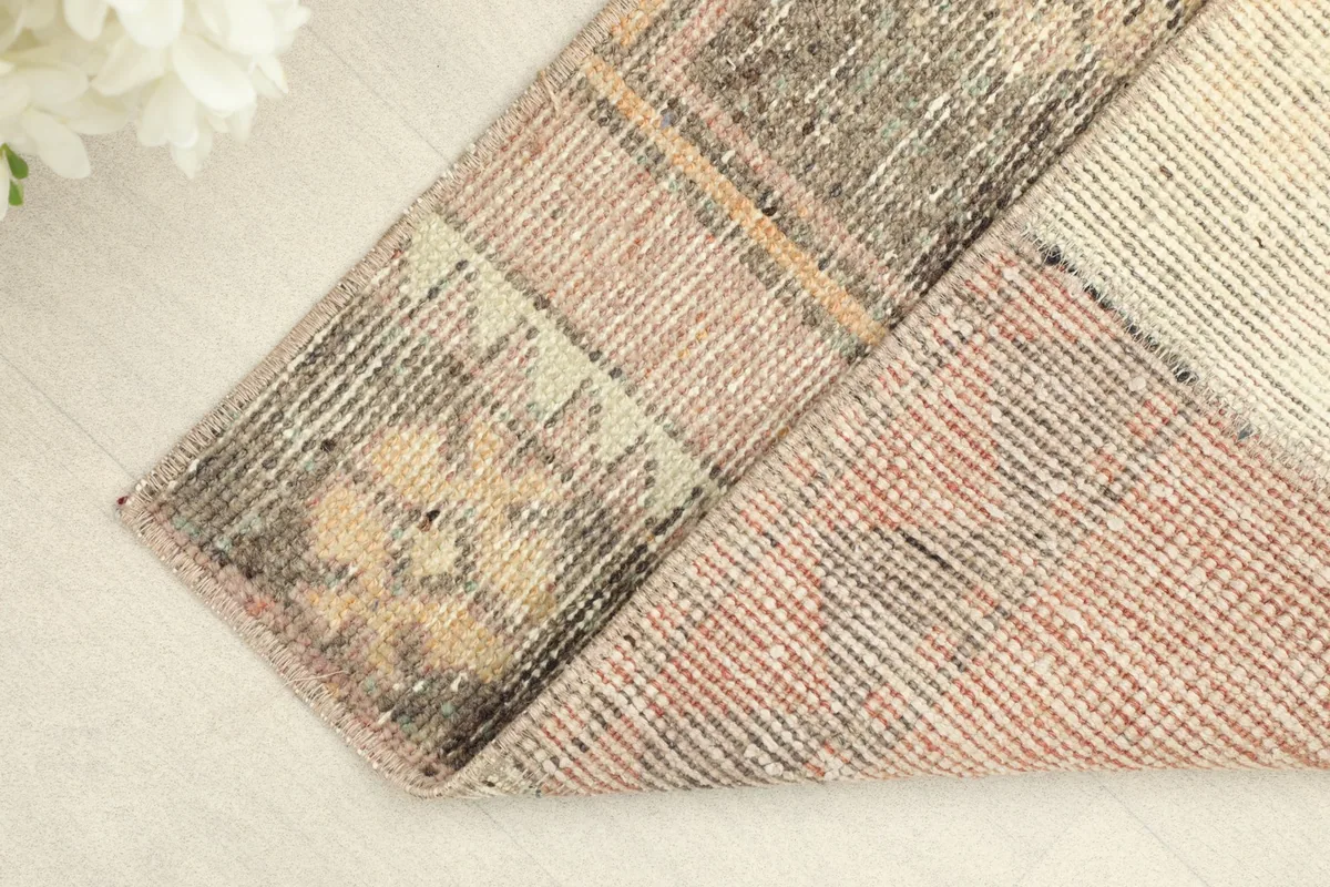 Corner of the rug folded back, revealing the cotton foundation and the reverse side.