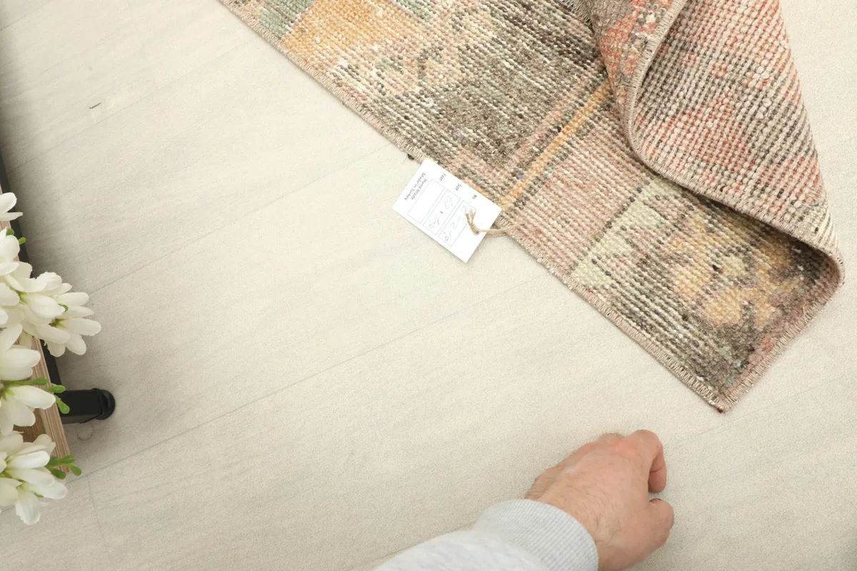 Hand pointing to the rug's label, indicating its authenticity and origin.