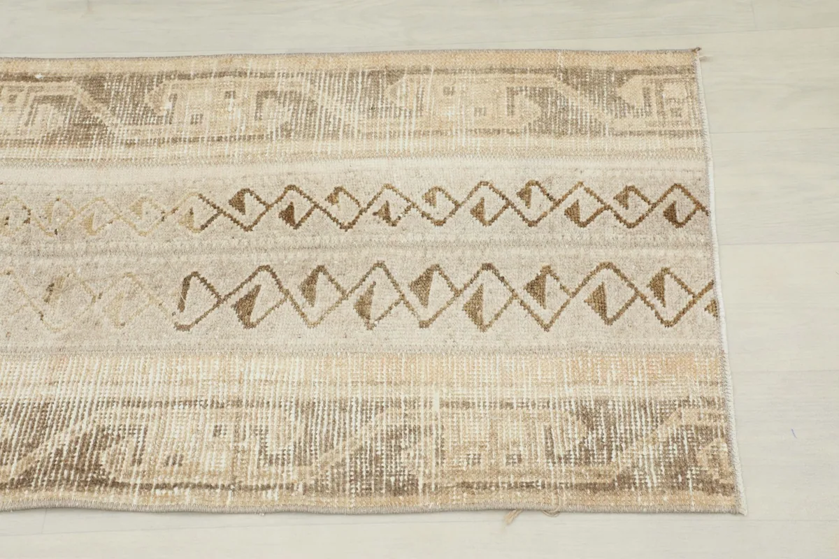 Close-up of the rug's central design, showing tan and beige geometric patterns.