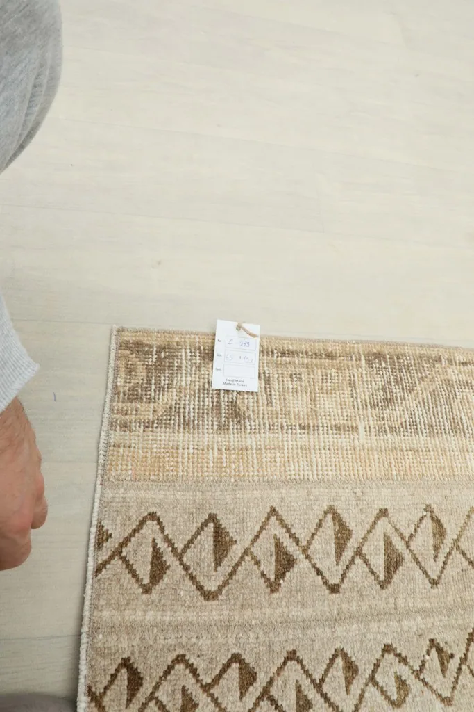 Overhead view of a section of the rug, with a hand pointing to the texture and details.