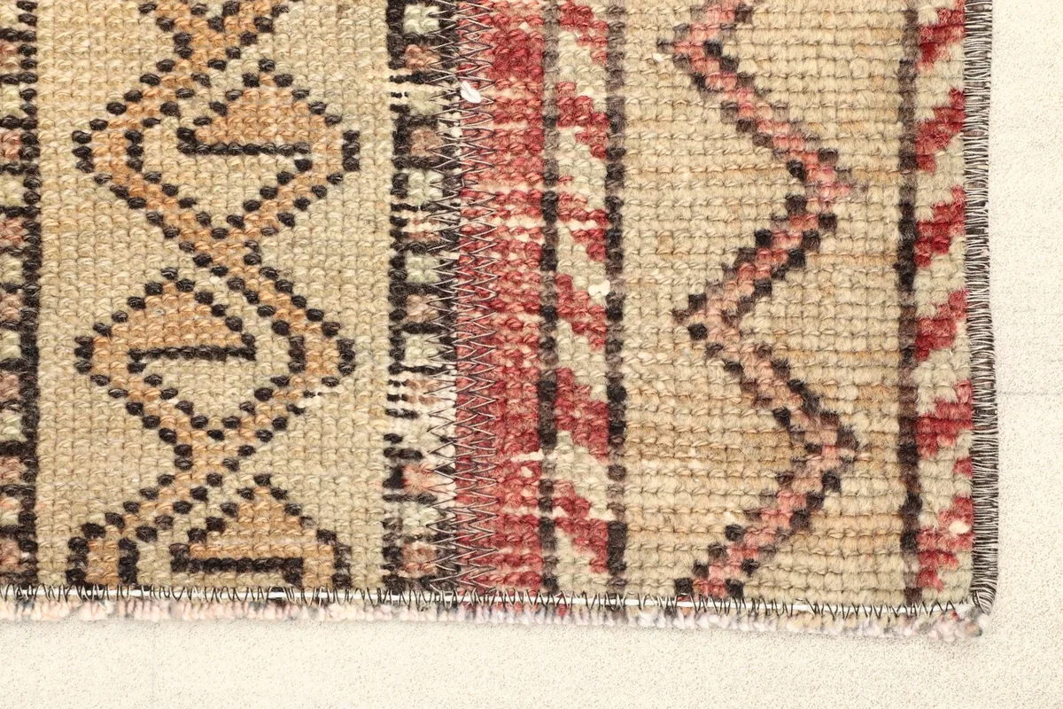 Close-up detail of the rug's edge, showing the hand-knotted wool pile and geometric patterns.