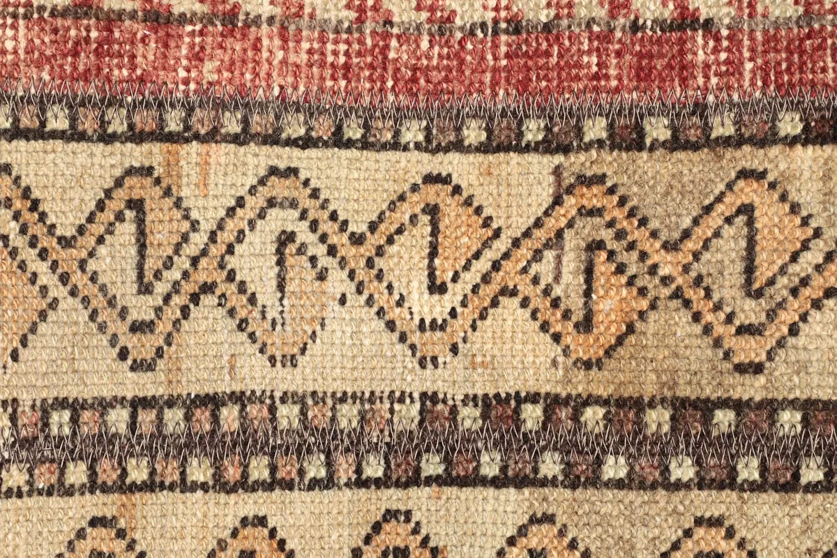 Detailed view of the central tribal motifs within the beige and brown stripes of the rug.