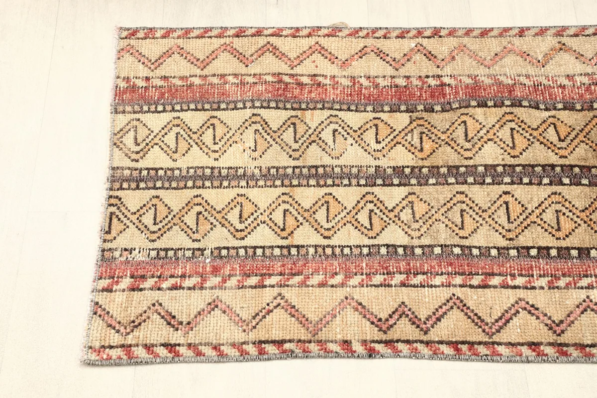 View of one end of the rug, showing the continuation of the striped design and minor wear.