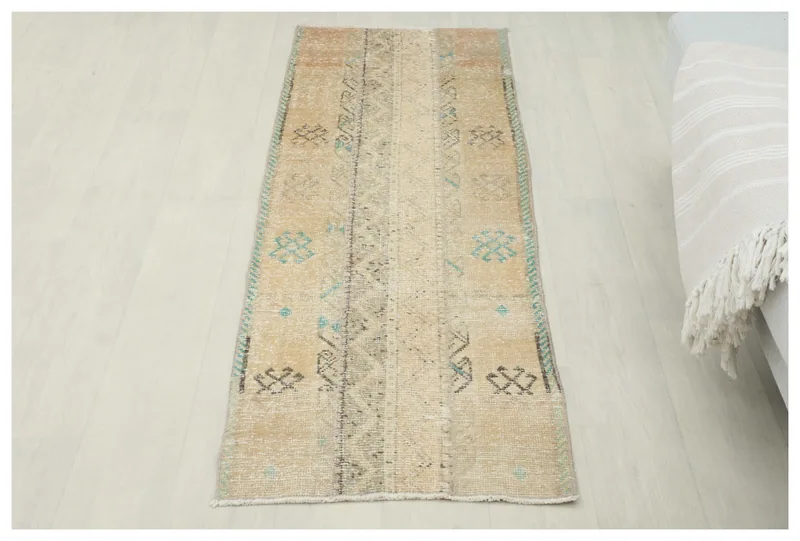 Full overhead view of the beige tribal geometric runner rug on a white floor.