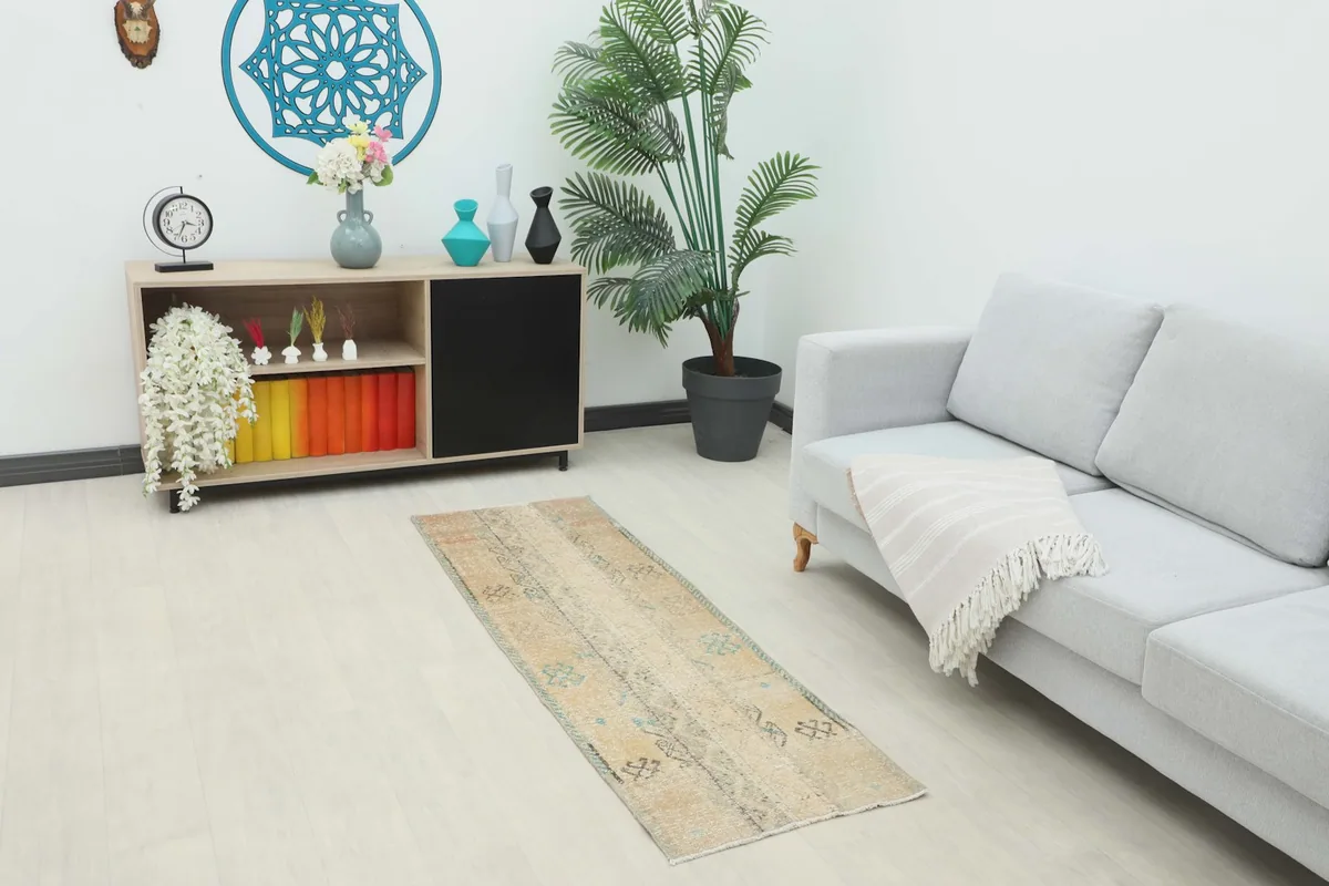 Beige runner rug placed in a modern living room setting next to a gray sofa and wooden cabinet.