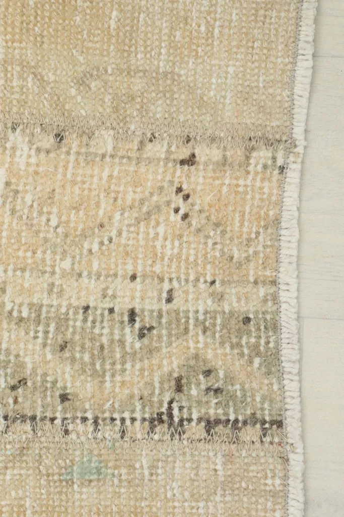 Detail of the rug's short, natural fringe and the finished edge on one side.