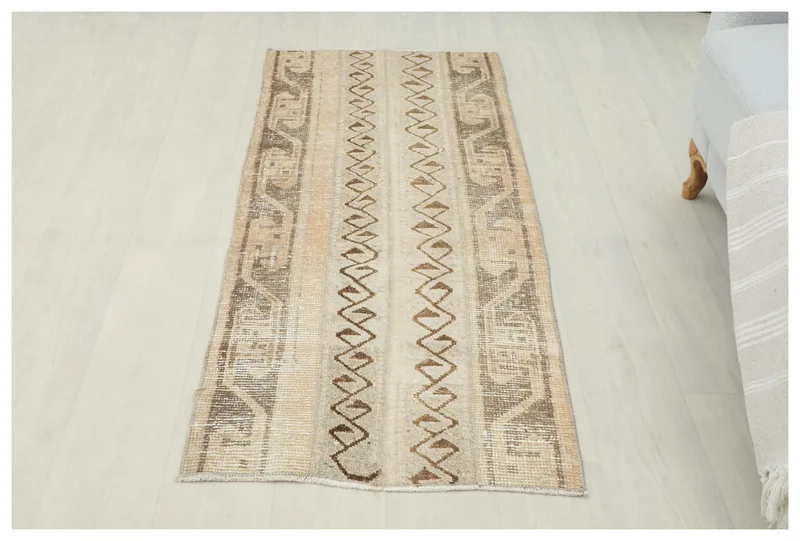 Full top view of the 2x5 beige and brown geometric vintage Anatolian area rug on a white floor.