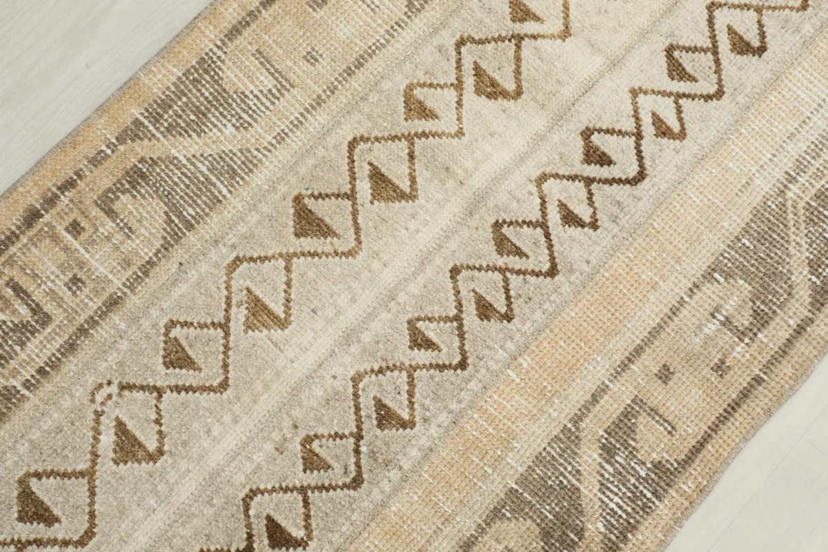 Diagonal close-up of the hand-knotted wool pile and the intricate geometric motifs on the rug.
