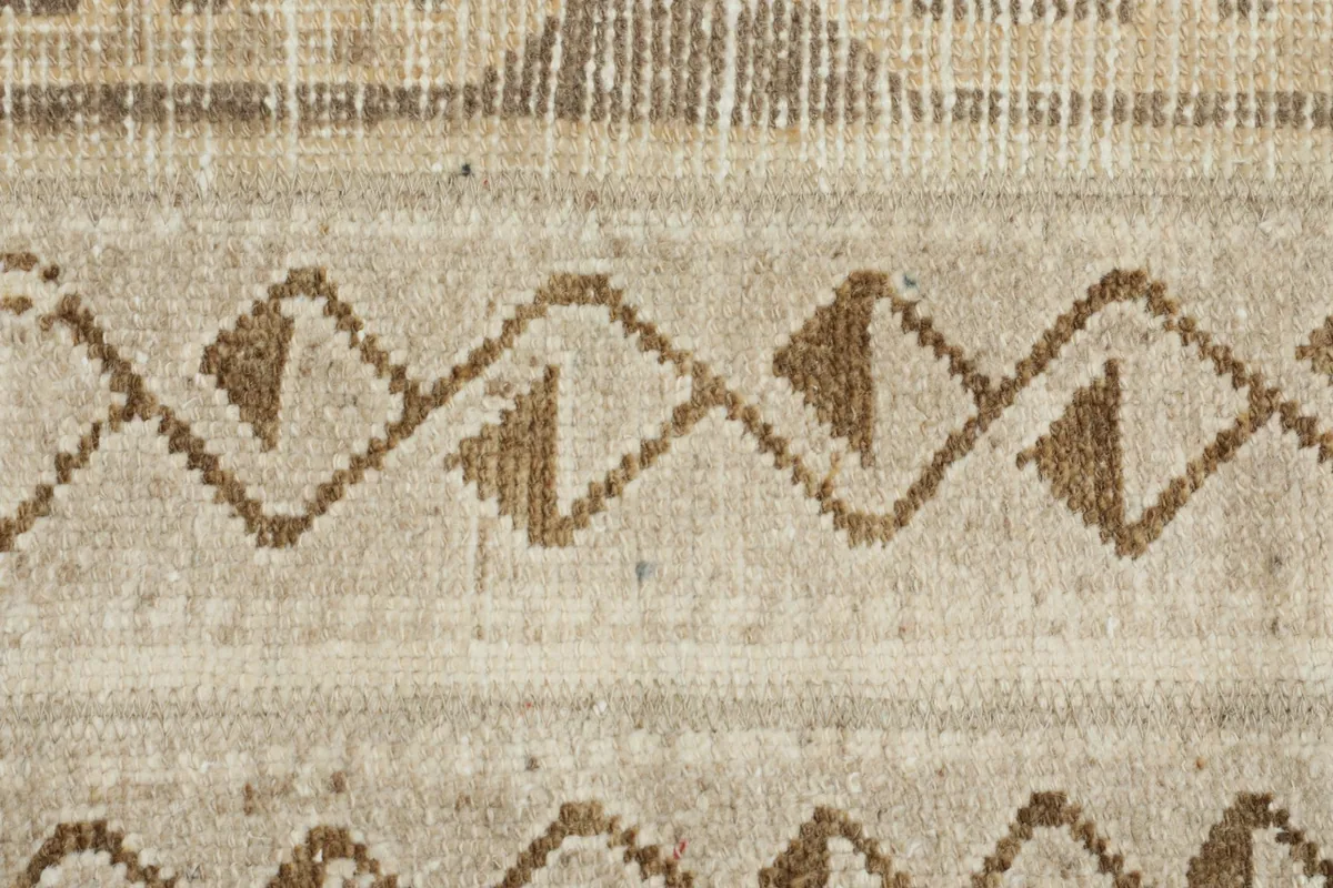 Extreme close-up showing the low pile texture and individual knots of the vintage wool rug.