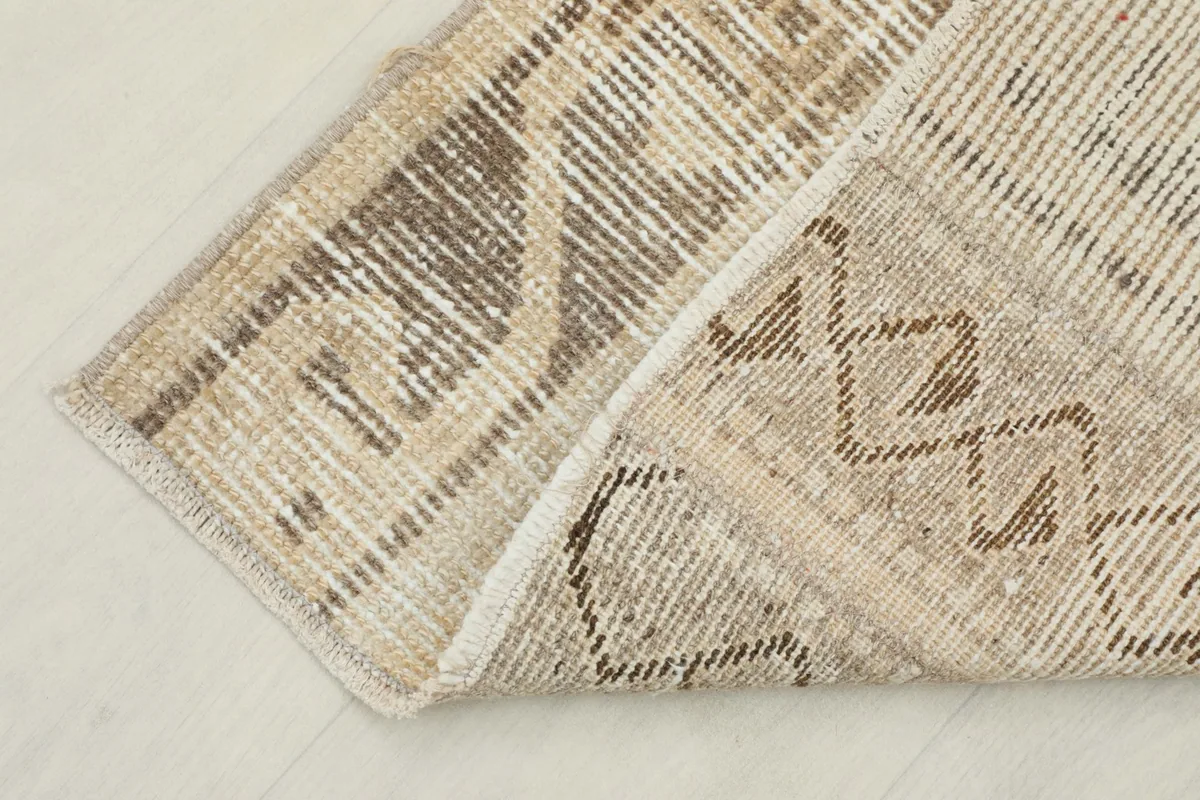 Corner of the rug folded back to show the cotton foundation and the reverse side of the hand-knotted construction.