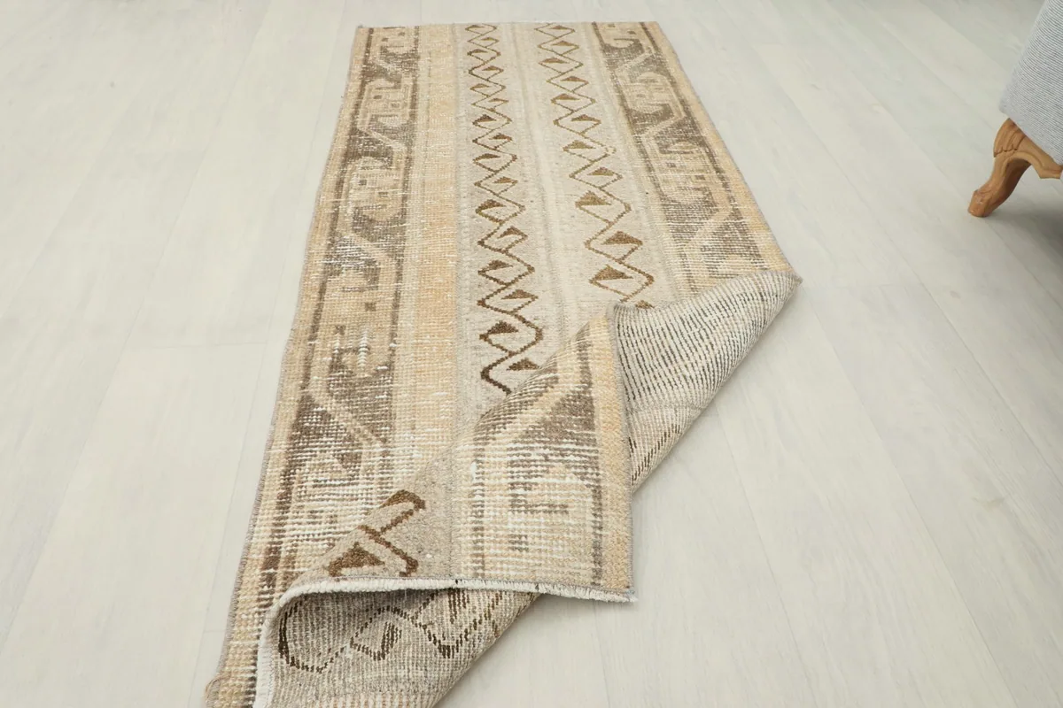 The vintage Anatolian rug partially folded, displaying both the top surface and the underside.