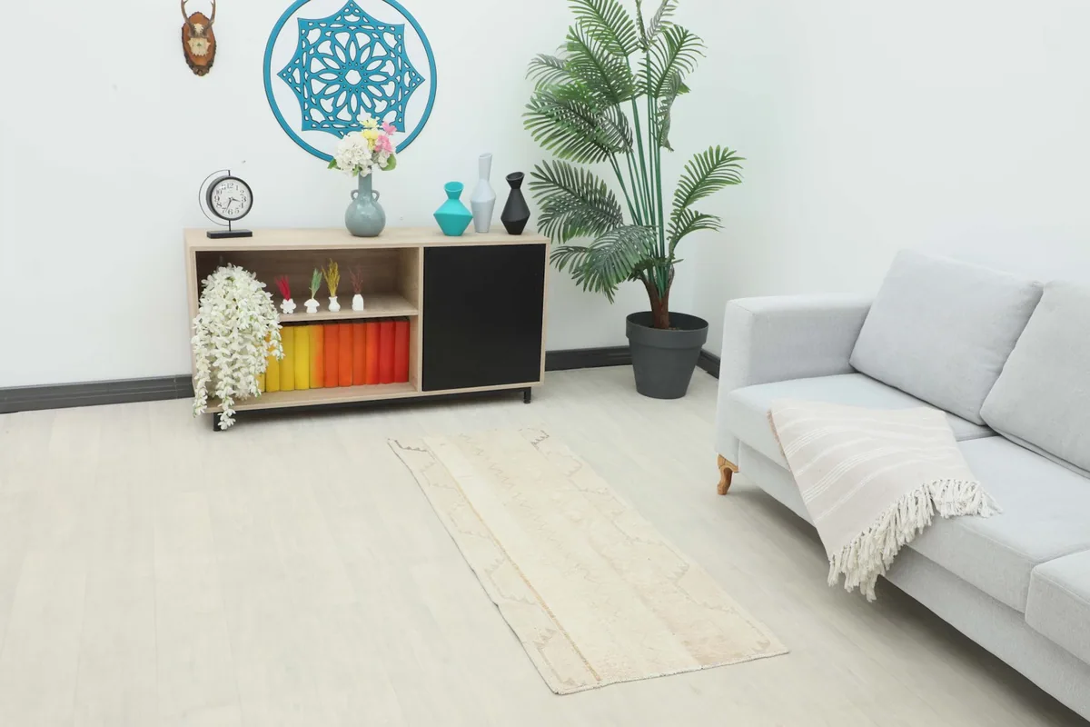 Vintage beige runner rug in a living room setting, placed in front of a sofa and cabinet.