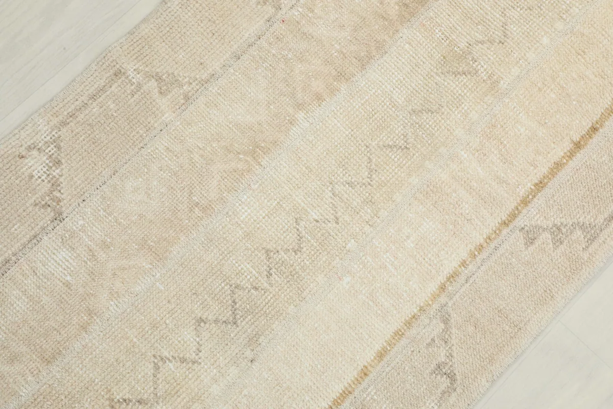 Overhead close-up showing the low wool pile and subtle chevron and tribal motifs of the runner.