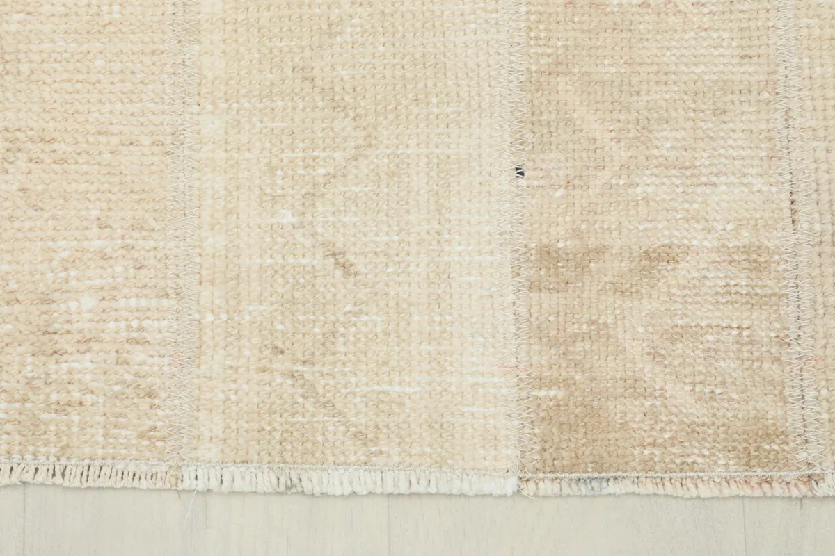 Close-up of the short, natural cotton fringes and the hand-knotted structure at the rug's edge.
