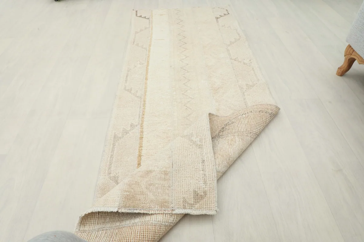 Runner rug partially folded, showing the flexibility and thickness of the vintage wool material.