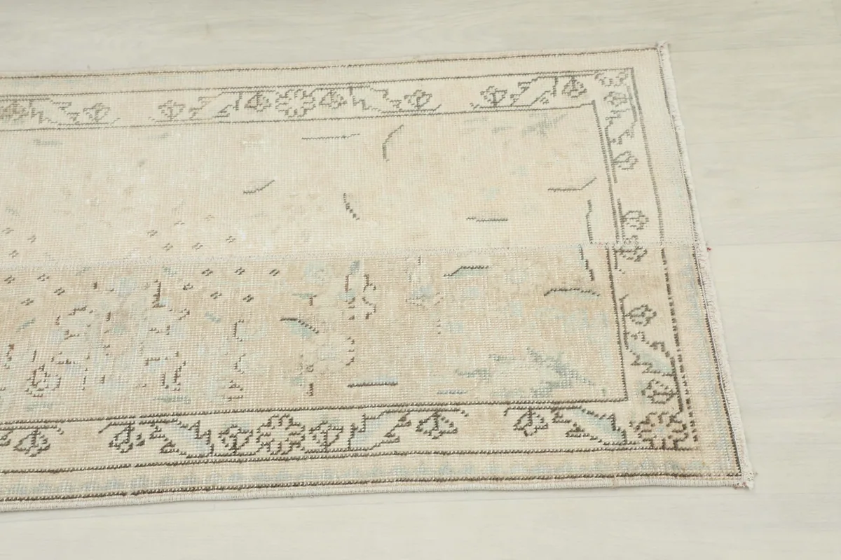 Close-up of the runner's border and a section of the beige field with faded geometric motifs.