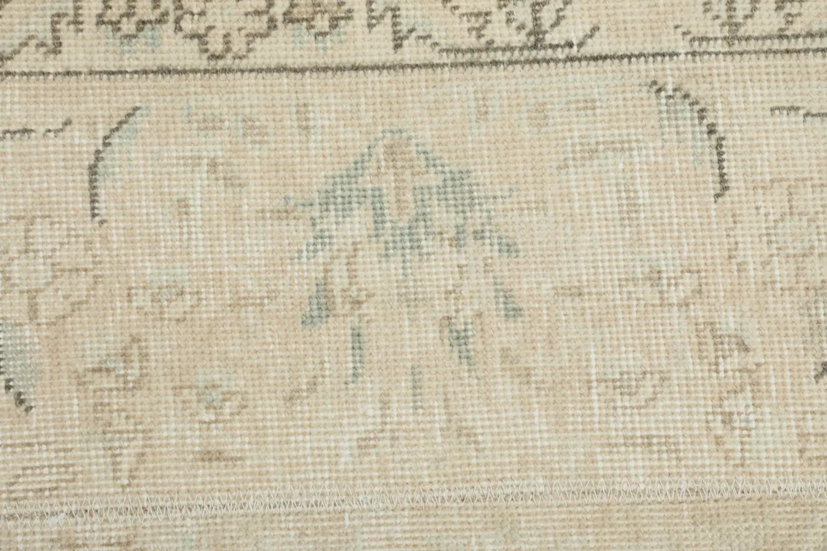 Close-up of a specific tribal motif in faded blue and beige, highlighting the hand-knotted wool.