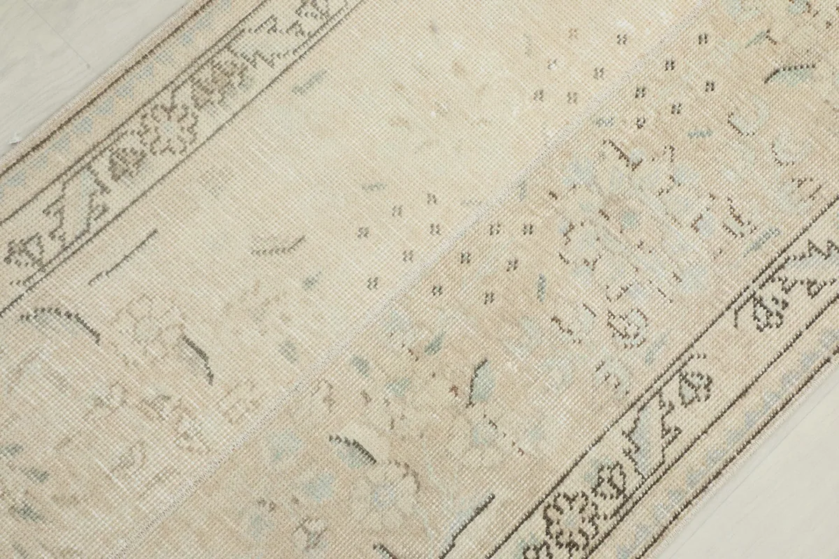Overhead close-up showing the low pile texture and the aged appearance of the beige and gray motifs.