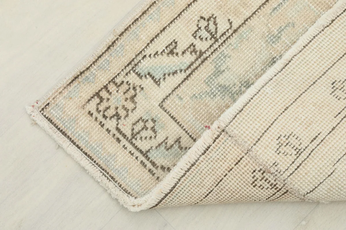 Corner of the rug folded back to reveal the cotton foundation and the reverse side of the hand-knotted pile.