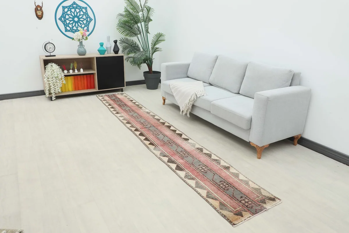 Long shot of the rose and gray runner rug placed in a modern living space with a light gray sofa.