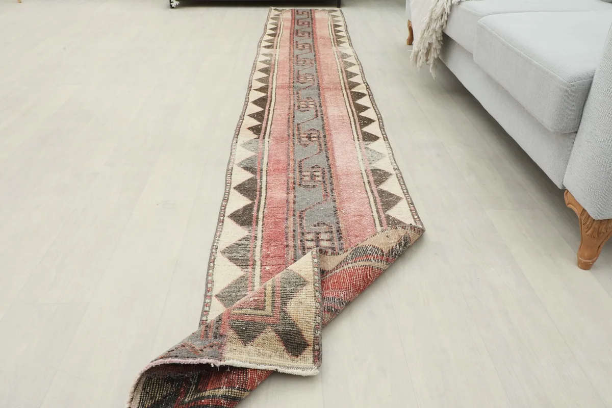 Angled view of the runner rug in a room setting, with one end slightly folded, showing its full length.