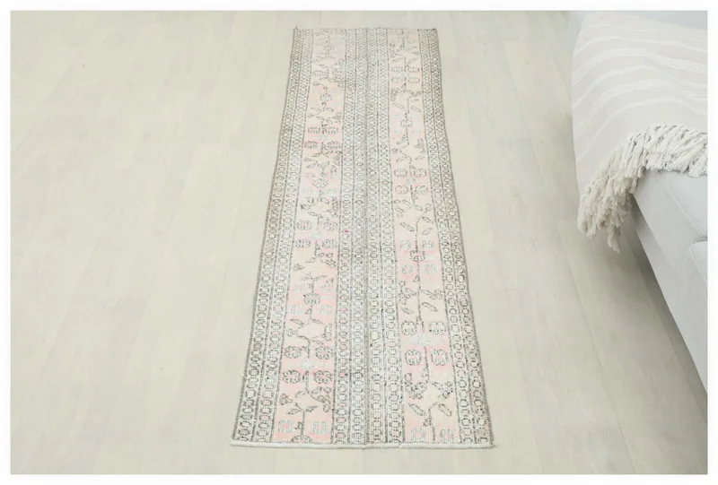 Full top view of the 1'8" x 6'11" vintage pink and gray floral geometric runner rug on a white floor.
