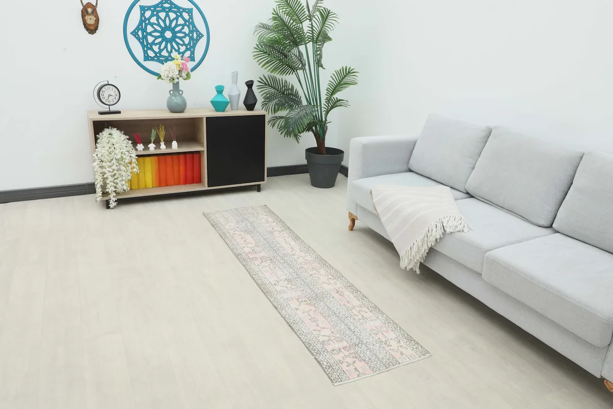 Vintage pink and gray runner rug placed in a living room setting next to a light gray sofa.