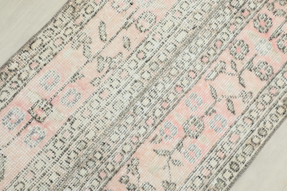 Overhead view showing the repeating floral and geometric patterns in pink and gray tones.