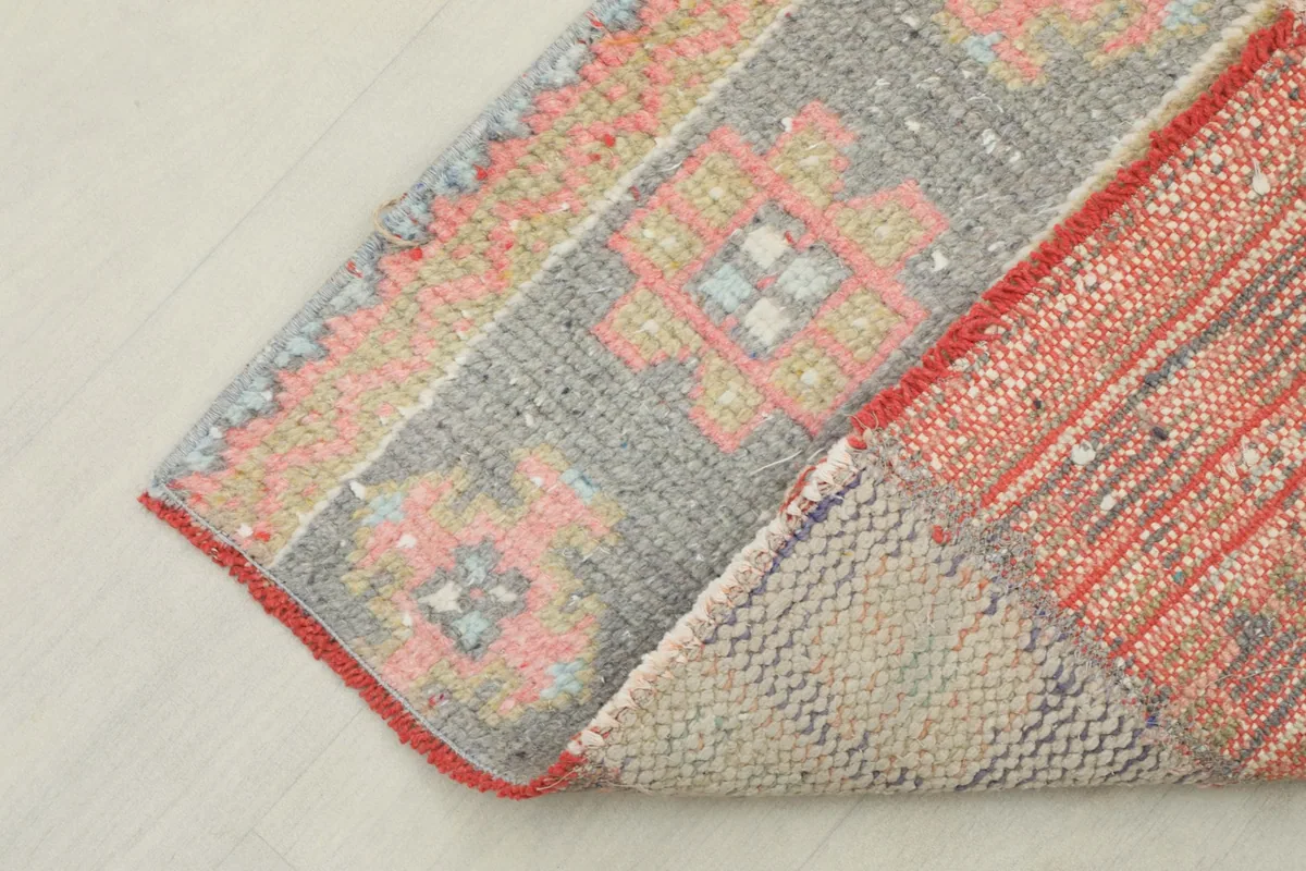 Corner of the runner rug folded to show the cotton foundation and reverse side of the knotting