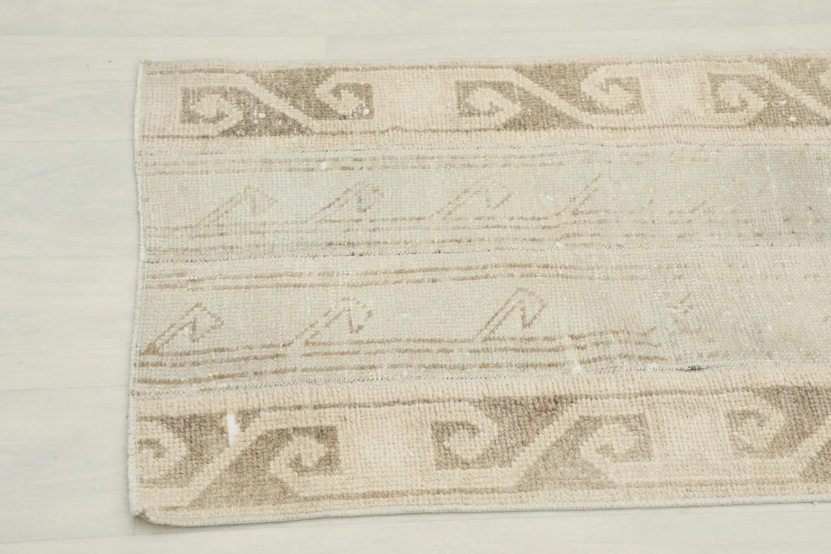 Detailed view of the rug's vintage patina and subtle variations in the beige and tan colors.